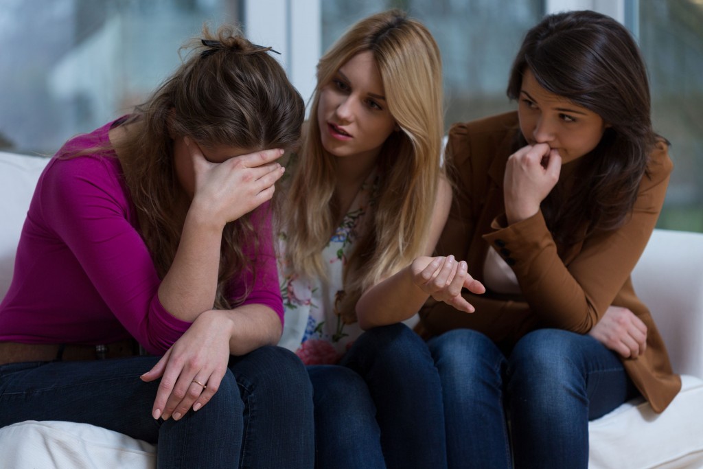 a woman telling her friends she has cancer and receiving support and comfort